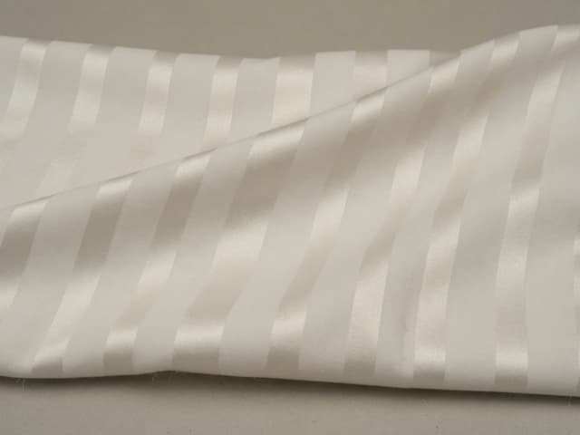 Ivory polyester with tone-on-tone satin-float bands on a plainer ground. Program illustration, not a named mill roll.